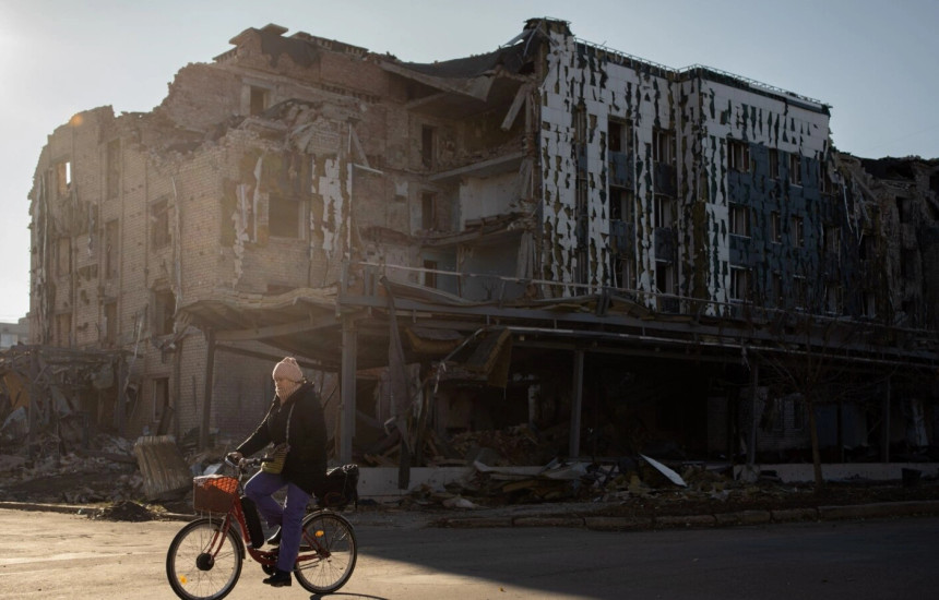 Një banore vendëse kalon me biçikletë pranë një dyqani dhe restoranti të shkatërruar në qytetin e Ukrianës, Pokrovsk, më 19 nëntor 2024.
