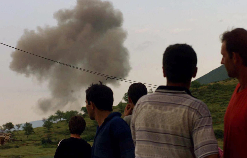 Qytetarët shqiptarë shikojnë një re të madhe tymi pasi një aeroplan luftarak i NATO-s thuhet se goditi caqet serbe pranë kufirit midis Shqipërinë e Kosovës në Morinë, në Shqipërinë veriore, të hënën, 31 maj 1999 (Foto: Associated Press / Luca Bruno)