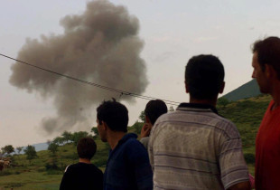 Qytetarët shqiptarë shikojnë një re të madhe tymi pasi një aeroplan luftarak i NATO-s thuhet se goditi caqet serbe pranë kufirit midis Shqipërinë e Kosovës në Morinë, në Shqipërinë veriore, të hënën, 31 maj 1999 (Foto: Associated Press / Luca Bruno)