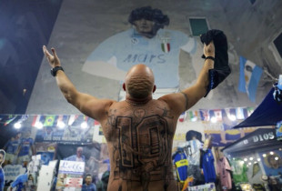 Një tifoz hap duart dhe nderon muralin ku është Maradona. Ai ka tatuazh në shpinë numrin që e bartte legjenda argjentinase.