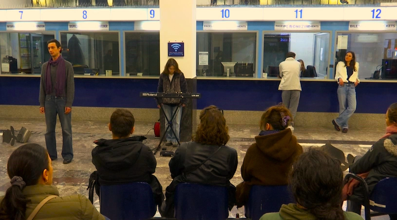 Hapësira pranë sporteleve 7 deri 12 në Stacionin e Autobusëve në Prishtinë është kthyer në skenë. Performuesja dhe performuesi kanë qëndruar në skajet e së njëjtës vijë, teksa muzika e butë e një sinti krijon pulsin që e mban publikun të heshtur