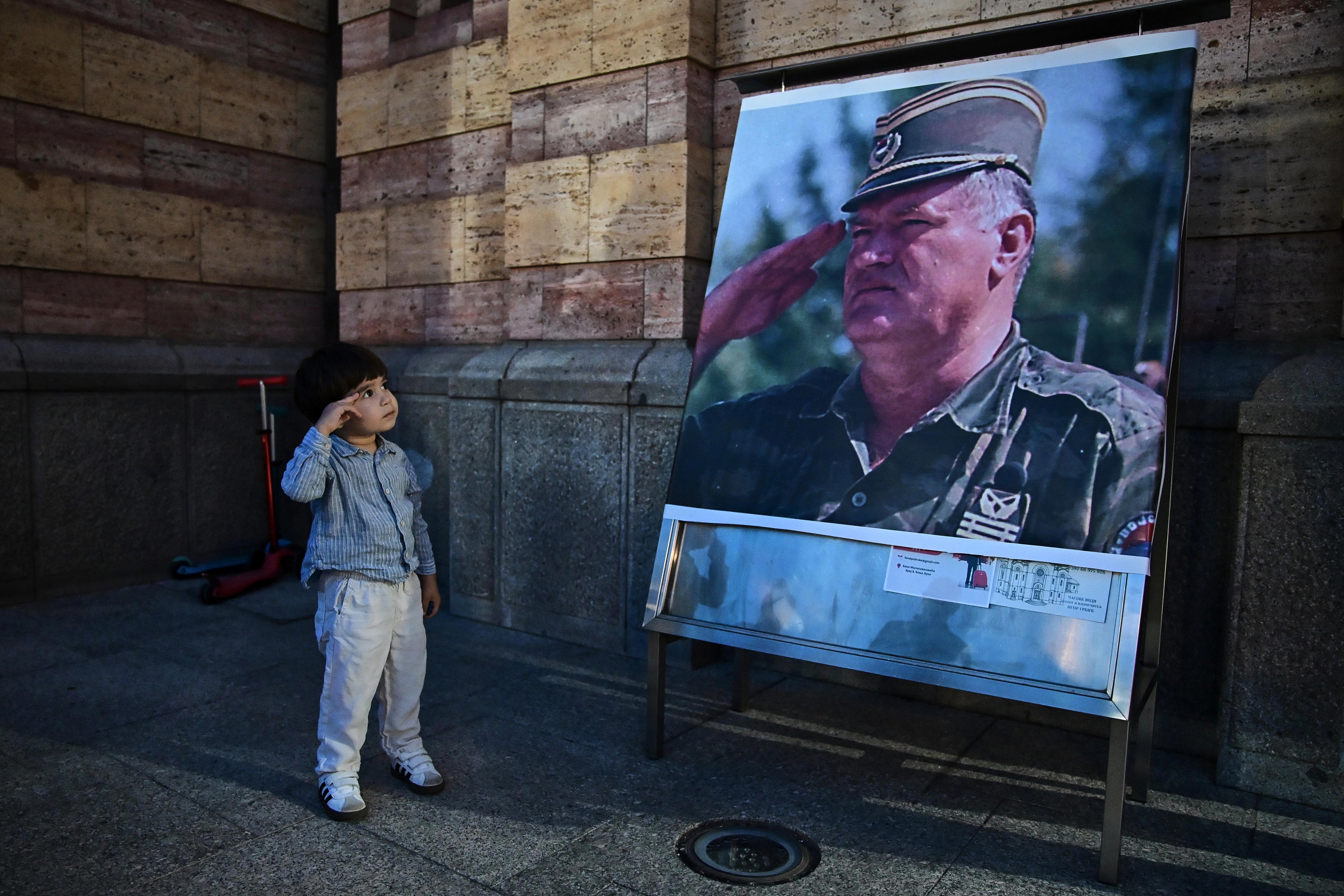 Një fëmijë me përshëndetje ushtarake para fotografisë së kriminelit, Ratko Mlladiq jashtë një kishe në Banjallukë të Bosnjë-Hercegovinës. Foto: AP